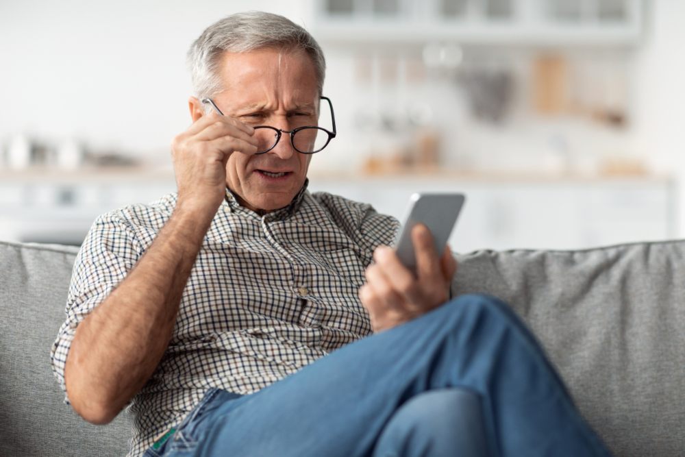 moški slabo vidi na telefon in se sprašuje, kako naj poskrbi za izboljšanje vida