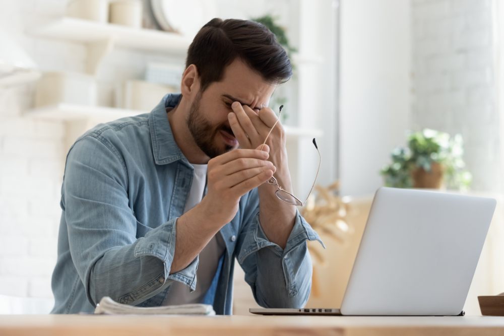 utrujene oči in digitalni stres pri mladem moškem za računalnikom